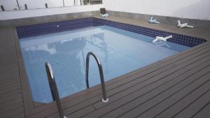 a large swimming pool with blue tiles on a wooden deck at Trevo De Arraial pousada em cabo frio in Cabo Frio