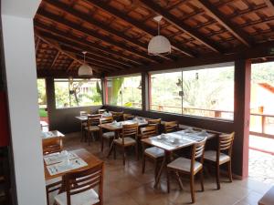 a dining room with tables and chairs and windows at Pousada do Grande Lago in Lindóia