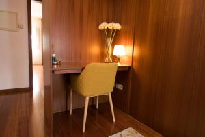 a desk with a yellow chair and a vase of flowers at Casas do Paço - Philosophy Apartments in Braga
