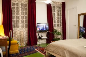 - une chambre avec des rideaux rouges, un lit et une télévision dans l'établissement 46FM : Montauban Guest House, à Montauban