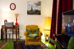 un salon avec une chaise et une télévision dans l'établissement 46FM : Montauban Guest House, à Montauban