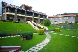 a large building with a staircase in front of a yard at Green Pastures - A Hill Country Resort in Kodaikānāl
