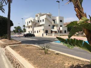 a building with a car parked in front of a street at Apartment "Las Palmeras" in Los Alcázares