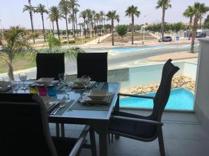 a dining table and chairs with a view of a pool at Apartment "Las Palmeras" in Los Alcázares