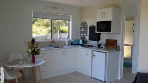 a kitchen with white cabinets and a table and a window at Four Huia in Oneroa