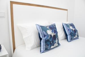 a bed with three blue and white pillows on it at Casas do Paço - Philosophy Apartments in Braga