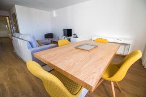 a dining room with a wooden table and yellow chairs at Casas do Paço - Philosophy Apartments in Braga