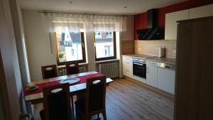 uma cozinha com mesa e cadeiras e uma cozinha com fogão em Gästehaus Sylvia em Kelberg