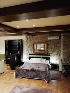 a bedroom with a large bed and a stone wall at Nymfes Hotel in Kato Loutraki