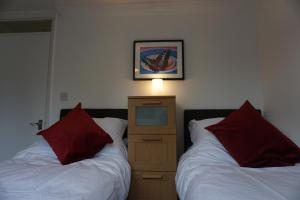 a bedroom with two beds and a dresser with red pillows at Holt Apartment in Bristol