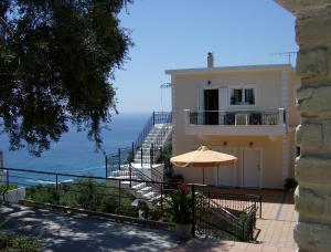 a house with an umbrella and a view of the ocean at Studios Nikolaou Bros in Parga
