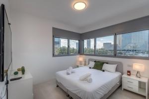 una camera con un letto bianco e alcune finestre di Beautiful Sunny 3 bedrooms in font of the beach a Tel Aviv