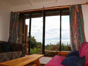 a living room with a couch and a large window at Shambhala Cabins in Onekaka