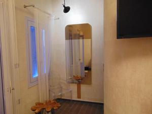 a bathroom with a mirror and a chair next to a window at AMO Folegandros in Karavostasi