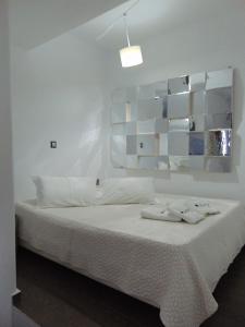 a white bedroom with a bed with white sheets at AMO Folegandros in Karavostasi