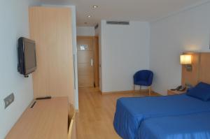 Schlafzimmer mit einem Bett, einem Schreibtisch und einem TV in der Unterkunft Hotel del Port in Sant Carles de la Ràpita