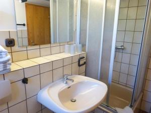 ein Bad mit einem Waschbecken, einem Spiegel und einer Dusche in der Unterkunft Ferienwohnung Anne in Nebel