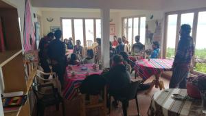 een groep mensen die aan een tafel in een kamer zitten bij Hostal Inti Wayra in Comunidad Yumani