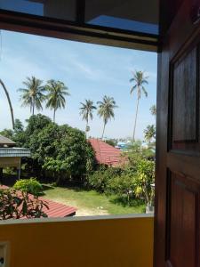 een raam met uitzicht op palmbomen bij Rumah Hentian Ayah in Kampung Kuala Besut