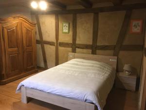 a bedroom with a white bed with a wooden cabinet at Gite d'Audrey et Jean in Uttenheim