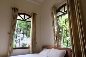 a bedroom with two large windows and a bed at Moon house tropical garden - West side in Nha Trang