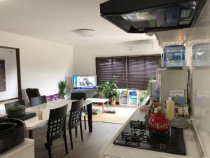 a kitchen with a stove and a table with chairs at Yoko House in Uruma