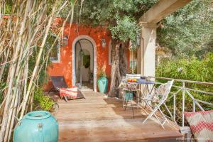 Casa de color naranja con porche de madera con mesa y sillas en Le Mini Cottage en Bastia