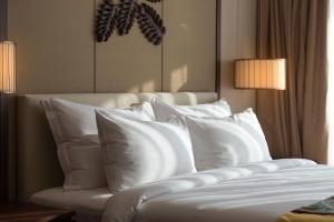 Jing Shang Hotel في سيهانوكفيل: غرفة نوم بسرير ومخدات بيضاء