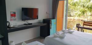 a room with a tv and a table with a bed at Thip Buri Riverside in Sichon
