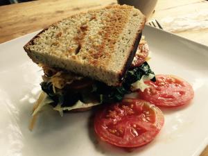 a sandwich with tomatoes on a white plate at Karungi Camp in Rubuguli