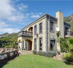 a large house with a balcony on top of a yard at Casa a Capri, Capri Village, Cape Town in Fish hoek