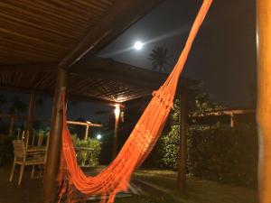 an orange hammock on a patio at night at Paraiso dos Corais in Guarajuba