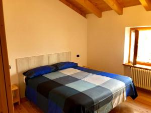 a bedroom with a bed with blue pillows and a window at B&B Villa Dalegno in Temù