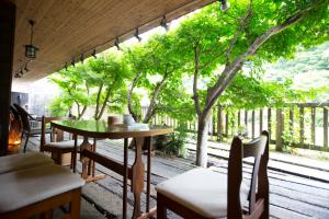 eine Terrasse mit einem Tisch, Stühlen und Bäumen in der Unterkunft Shiobara Onsen Ryokan Kamiaizuya in Nasushiobara