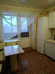 ベルツクにあるАпартаменты на Лунной возле "Зима-Лето"のキッチン(テーブル、冷蔵庫付)、窓が備わります。