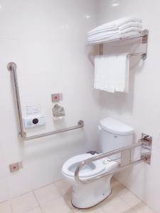 a white bathroom with a toilet and towels at The Koos Hotel in Xindian