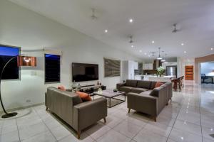uma sala de estar com dois sofás e uma televisão em Luxury Darwin City Lights Jacuzzi Central Location Large House New Furnishings em Darwin