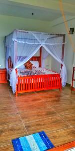 a bedroom with a red bed with a canopy at Divine View Homestay in Ella