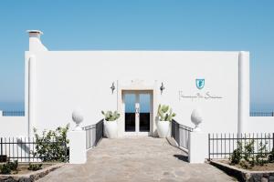 a white house with a door and a walkway at Principe Di Salina Boutique Hotel in Malfa