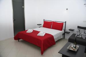 a bedroom with a red and white bed and a couch at Aurora Luxury Studio in Rhodes Town