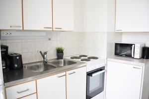 a white kitchen with a sink and a microwave at Hiisi Homes Lohja in Lohja