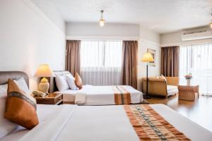 a hotel room with two beds and a couch at Markland Seaside Pattaya in Pattaya