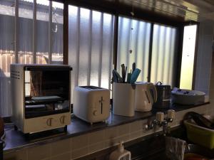 a kitchen counter with various appliances on a shelf at Hirauchi Hot Spot in Yakushima