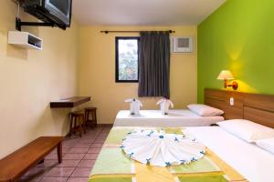 two beds in a room with green walls at Hotel Ponta das Toninhas in Ubatuba