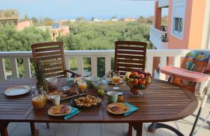 una mesa de madera con desayuno en el balcón en Kouros Chania Villas, en Máleme