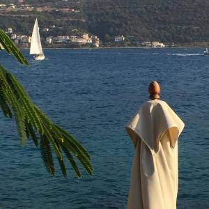a statue of a man in a cape looking at the water at Roditses Beach Sea Front Apartments in Samos