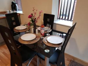 a dining room table with chairs and plates and wine glasses at Appleton Apartments in Newark-on-Trent