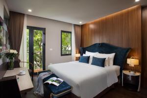 a bedroom with a large white bed with blue pillows at Hanoi L'Heritage Diamond Hotel & Spa in Hanoi