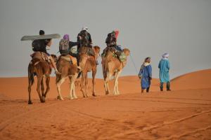 a group of people riding camels in the desert at Sahara Desert Experience camp in Merzouga +11 photos
