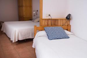 1 Schlafzimmer mit 2 Betten mit weißer Bettwäsche und einem blauen Kissen in der Unterkunft Hostal El Pozo in Chulilla